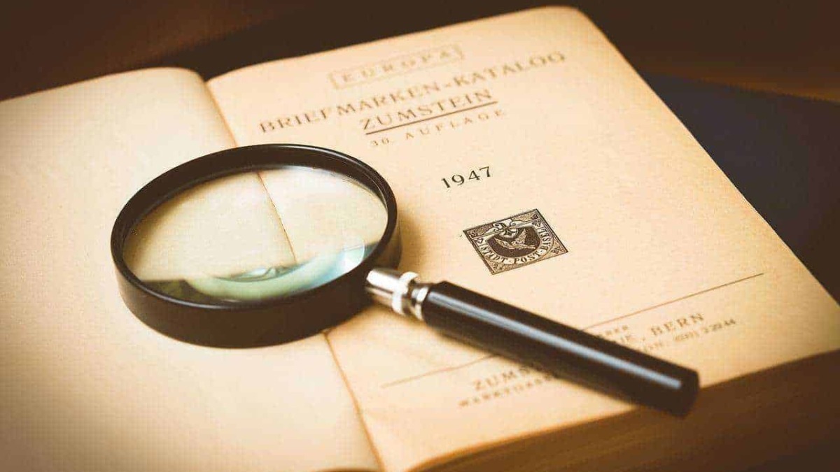 Libro antico aperto con lente d'ingrandimento su pagina, esplorazione storica e archivio documentale, focus su volumi di valore e ricerche approfondite.