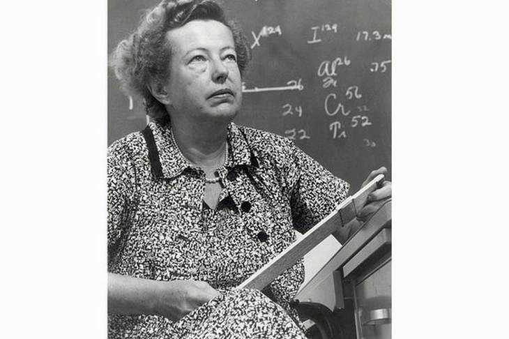 Matematica, insegnante donna con lavagna piena di formule matematiche scritte a mano.