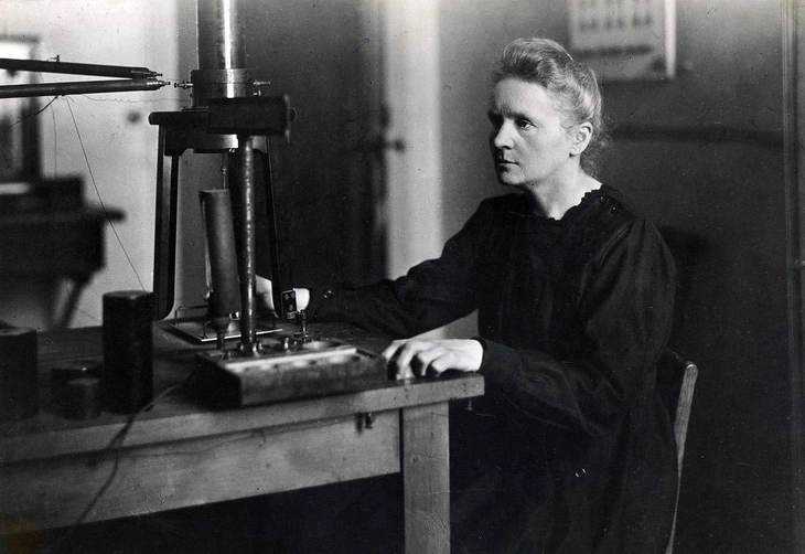 Innovativa scienziata donna al lavoro con strumenti di laboratorio in un'immagine storica in bianco e nero.