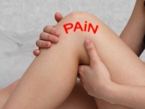 Dolore al ginocchio, mani che lo tengono, evidenziato con scritta rossa "PAIN" sulla pelle. Immagine rappresenta il dolore articolare e le issue ortopediche.