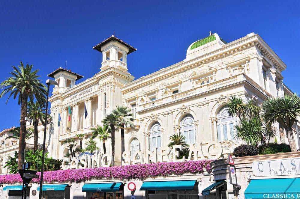 Casino di Sanremo, edificio storico con palme e fioriture colorate, situato in Riviera ligure, Italia, noto per l'architettura elegante e il fascino glamour del Casinò, al centro della vita mondana di Sanremo.