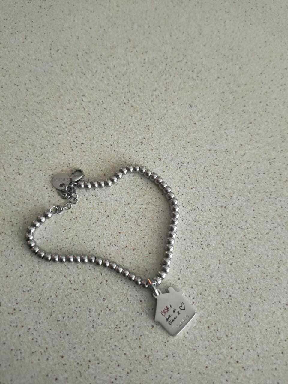 Bracciale con charm personalizzato in acciaio inox, elegante e adatto come regalo speciale, perfetto per occasioni romantiche o anniversari, sul tavolo di vetro.