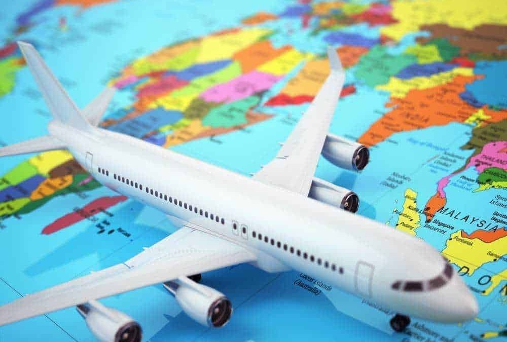 Aereo di plastica sopra una mappa del mondo colorata, simbolo di viaggi e avventure internazionali, con focus su destinazioni globali e cultura distintiva.