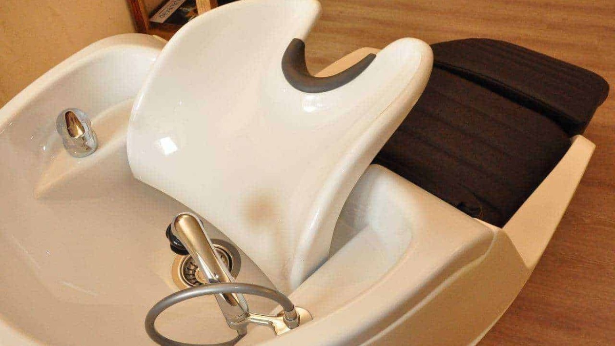 Lavatrice professionale da parrucchiere con rivestimento in legno, accessori e dettagli in acciaio inox, studiata per trattamenti di bellezza e cura dei capelli, ideale per saloni di parrucchieri.