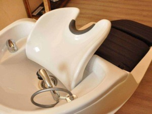 Lavatrice professionale da parrucchiere con rivestimento in legno, accessori e dettagli in acciaio inox, studiata per trattamenti di bellezza e cura dei capelli, ideale per saloni di parrucchieri.