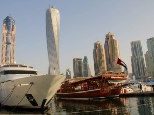 Yacht di lusso ormeggiata nel porto di Dubai con skyline di grattacieli moderni sullo sfondo.