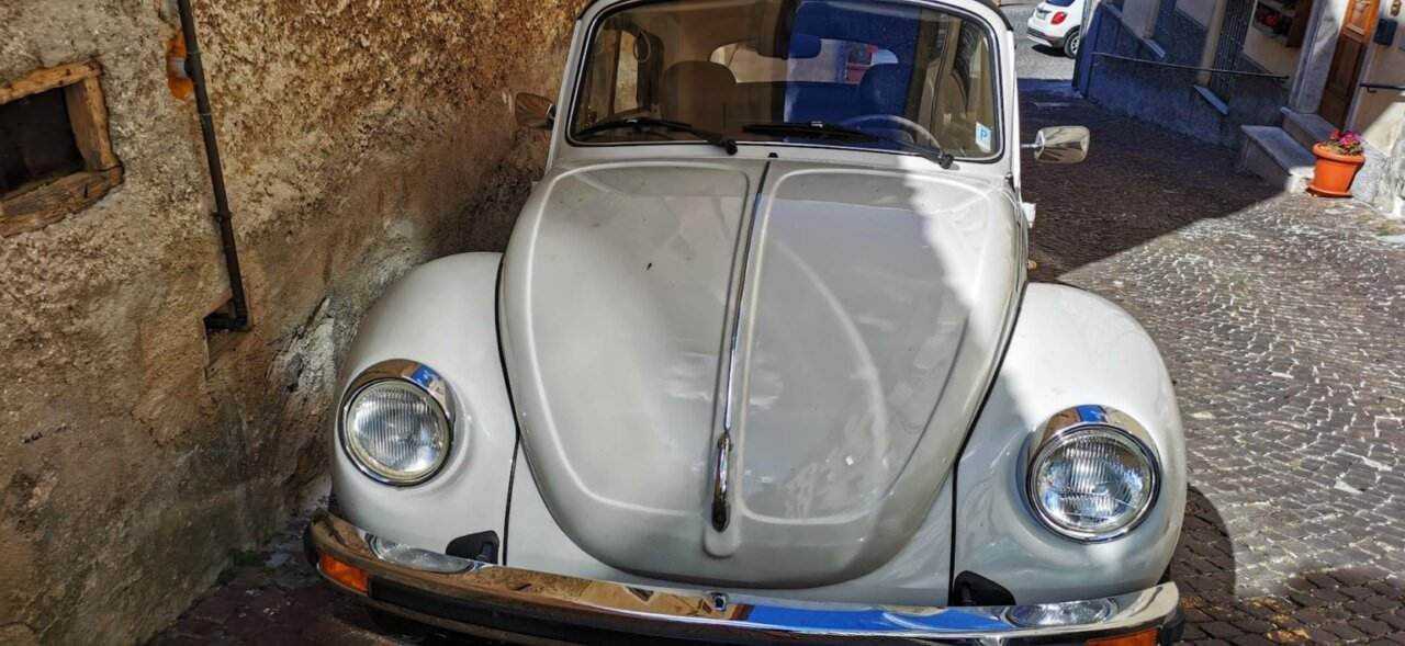 Storia del maggiolino Volkswagen, lo scarabeo d'epoca 2 Vw Maggiolone nero e bianco vintage parcheggiato su strada in pietra.
