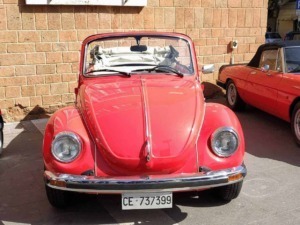 Volkswagen Maggiolino rossa d'epoca in esposizione di fronte a una parete di mattoni.
