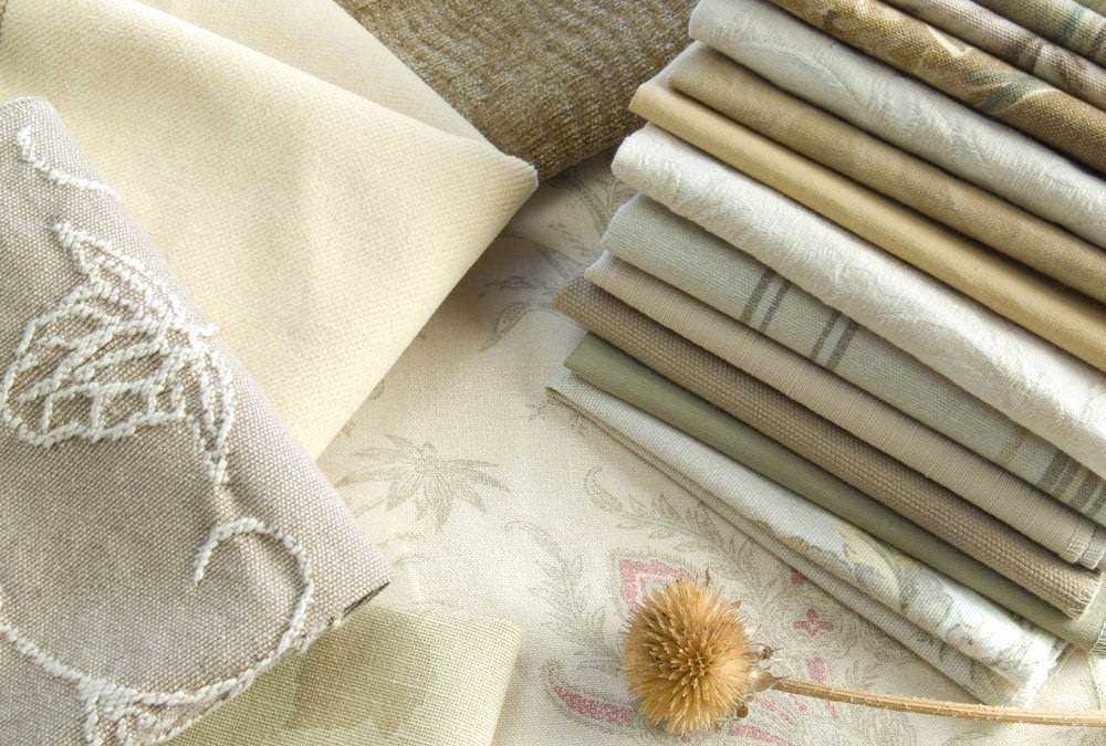 Morbide stoffe e tessuti decorativi in tonalità neutre e natura, perfetti per arredamento e home decor. Pieghe di tessuto eleganti e dettagli ricamati creano un'atmosfera accogliente.