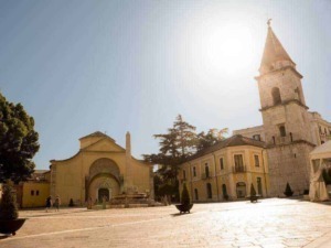 Antica piazza con torre storica e chiesa in stile medievale a Ragusa Ibla, Sicilia, al tramonto, con luce calda e atmosfera suggestiva.