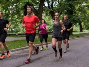 Allenamento di corsa all'aperto in parco con un gruppo di persone che praticano jogging per migliorare salute e benessere. Gruppo di runners che si allenano durante una passeggiata in natura.