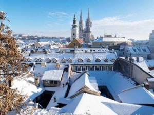 Tetti di case imbiancati dalla neve con vista sulla città e su chiese storiche, paesaggio invernale sereno e pittoresco, ideale per foto di viaggio e turismo invernale in città storiche italiane.