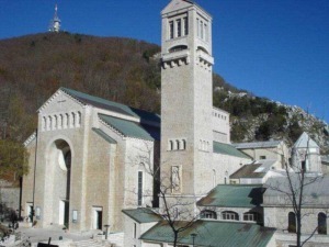 Storica chiesa in pietra con torre campanaria, situata in un paesaggio collinare, esempio di architettura religiosa in pietra, con dettagli architettonici tipici e una vista panoramica suggestiva.