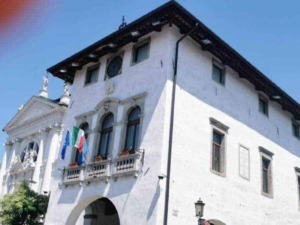 Palazzo storico con torre dell'orologio e bandiere italiane e europee, esempio di architettura tradizionale italiana a Belluno, Veneto, città con ricca storia e patrimonio culturale.