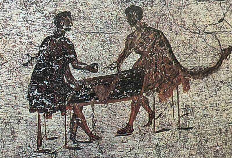 Frequenta scene di uomini e donne che condividono un momento di convivialità intorno a un tavolo, rappresentando un'epoca storica con dettagli autentici e un'atmosfera di intimità e amicizia.