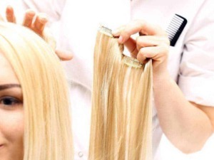Lunghezza capelli biondi con tessitura liscia, taglio e cura estetica capelli, servizio di extension o taglio professionale, immagine di una parrucchiera che applica extension su una cliente.