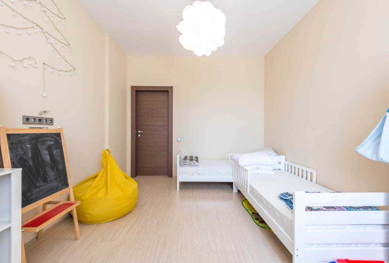 Letto singolo, cuscini e stanza dei bambini in stile minimalista, arredamento semplice e luci soffuse, ambiente accogliente e pulito.