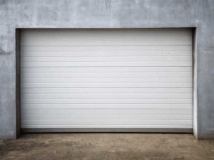 Porta sezionale moderna e automatizzata in un garage in cemento grigio, design minimalista e funzionale per amministratori di condomini.