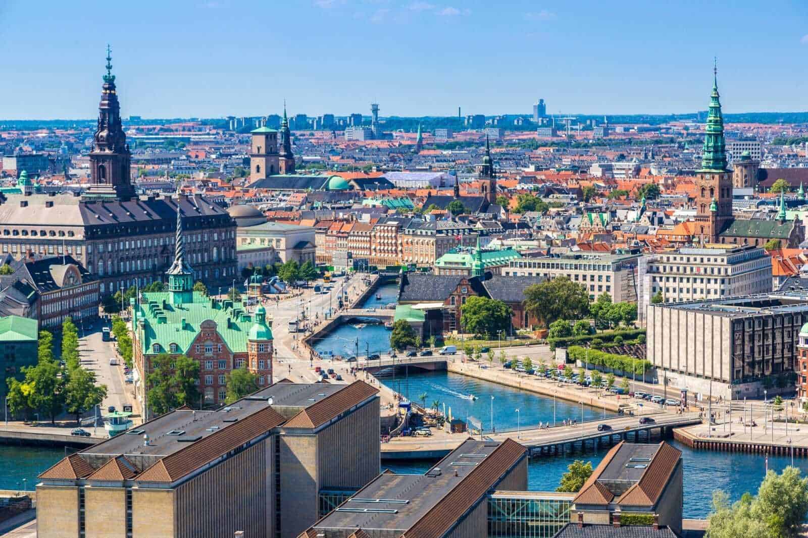 13 Città con canali nel mondo da vedere 9 VISTA PANORAMICA DELLA CITTÀ DI COPENHAGEN CON CANALI, TETTI COLORATI E STRUTTURE ARCHITETTONICHE ICONICHE NEL CUORE DANIMARCA, ILLUSTRANDO IL PAESAGGIO URBANO E CULTURALE.