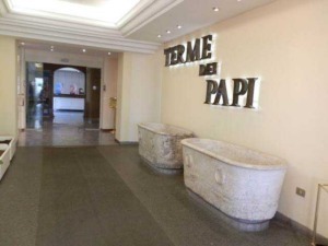 Faro di accoglienza in hotel con large lettere decorative "FIRME DI PAPI" e due grandi vasche in pietra in stile elegante, zona ingresso moderna e luminosissima, perfetta per accogliere gli ospiti.