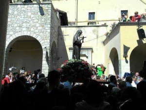 Festa religiosa con statua della Madonna di fronte a un grande pubblico, in un cortile storico con archi di pietra e persone che partecipano alla cerimonia, evento tradizionale in Italia.