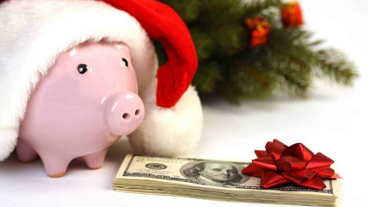 Salvadanaio a forma di maialino con cappello di Babbo Natale e decorazioni natalizie, denaro contante, regali di Natale e atmosfera festiva, simbolo di risparmio e festività.