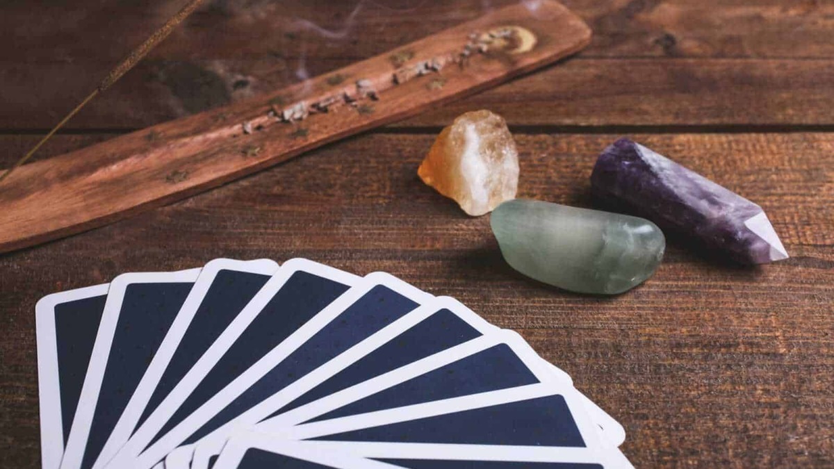 Preziosi cristalli e carte da Tarocchi su tavolo in legno per pratiche divinatorie e spirituali, ideale per appassionati di cartomanzia e rituali esoterici.