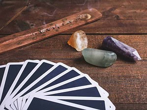 Preziosi cristalli e carte da Tarocchi su tavolo in legno per pratiche divinatorie e spirituali, ideale per appassionati di cartomanzia e rituali esoterici.