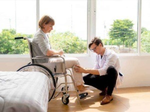 Assistente sanitaria che cura una paziente in sedia a rotelle in ambiente luminoso e accogliente. Cura e attenzione medica per persone anziane o con bisogni speciali.