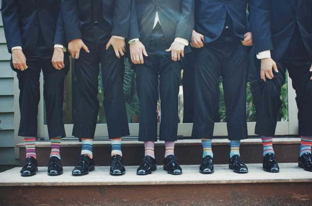 Diversi uomini in abito formale con calzature eleganti e calze colorate, in piedi su una scala all'aperto, simbolo di team, collaborazione e stile professionale.