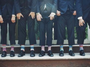 Diversi uomini in abito formale con calzature eleganti e calze colorate, in piedi su una scala all'aperto, simbolo di team, collaborazione e stile professionale.