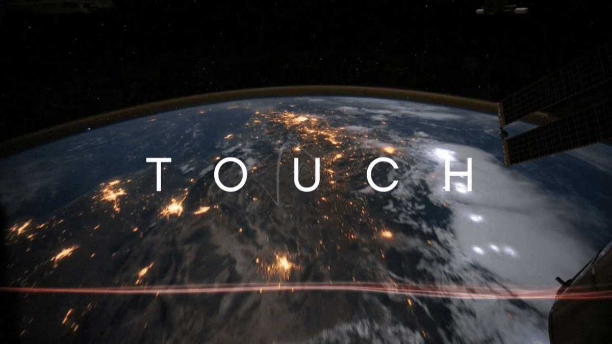 Vista dalla ISS con il pianeta Terra illuminato e la posizione dello spazioporto visibile, con il testo "TOUCH" sovrapposto all'immagine.