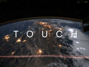 Vista dalla ISS con il pianeta Terra illuminato e la posizione dello spazioporto visibile, con il testo "TOUCH" sovrapposto all'immagine.