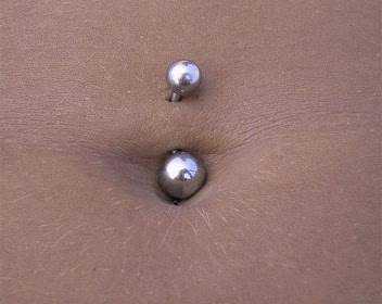Invenzione del piercing all'ombelico Piercing al ombelico con gioiello a sfera, dettaglio di body art e decorazione della pelle denim.