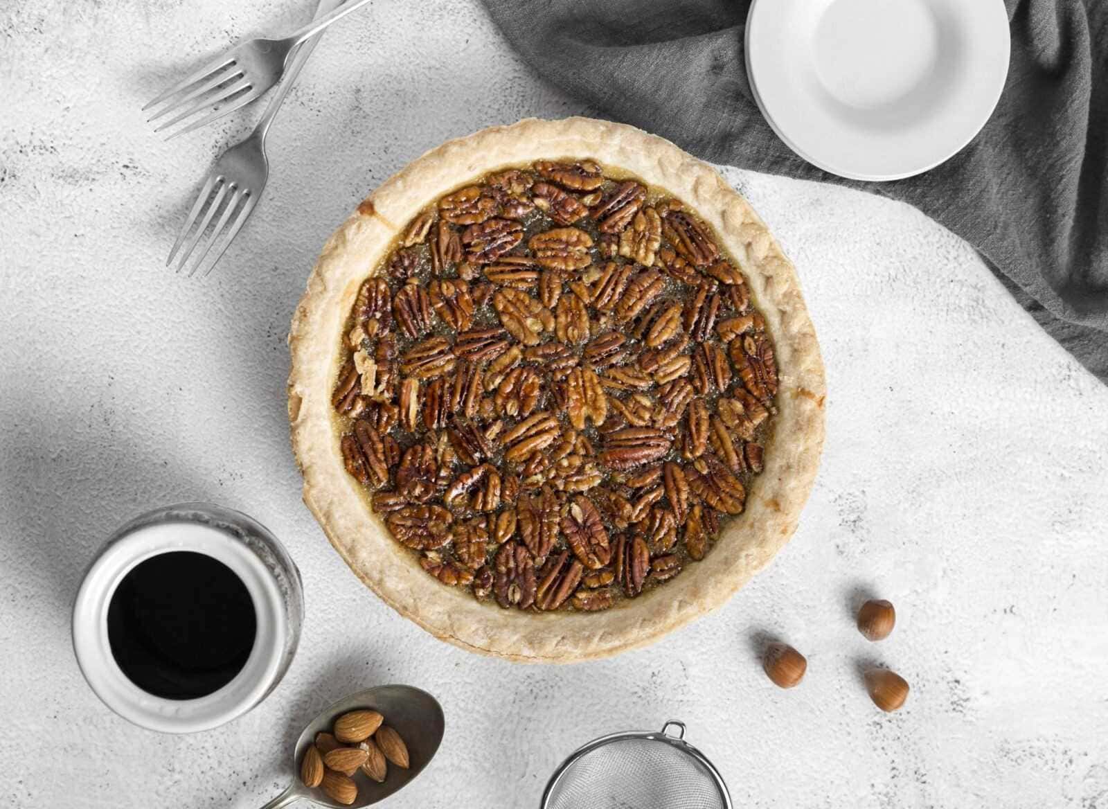 Pasta frolla con ripieno di noci pecan, torta golosa e croccante, accompagnata da caffè nero e mandorle, perfetta per colazione o dessert. Ricetta facile e irresistibile, ideale per gli amanti dei dolci alle noci.