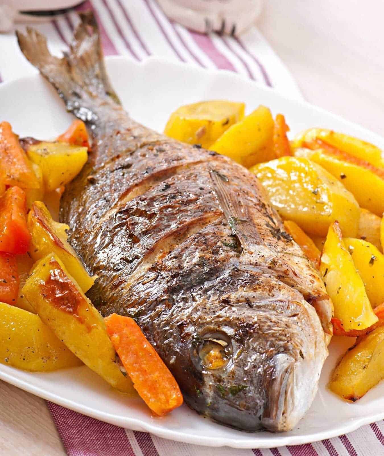 Pesce al forno con patate e carote, piatto tradizionale italiano ricco di sapore, ideale per una cena familiare.ate.