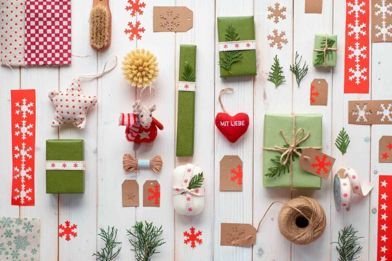 Fogli di carta decorativi natalizi, fiocchi di neve, nastri, fiocchi, decorazioni verdi, regali incartati, cuori di stoffa, muschio, nastri adesivi, bottoni, spugna, legno, per decorazioni di Natale fai da te.