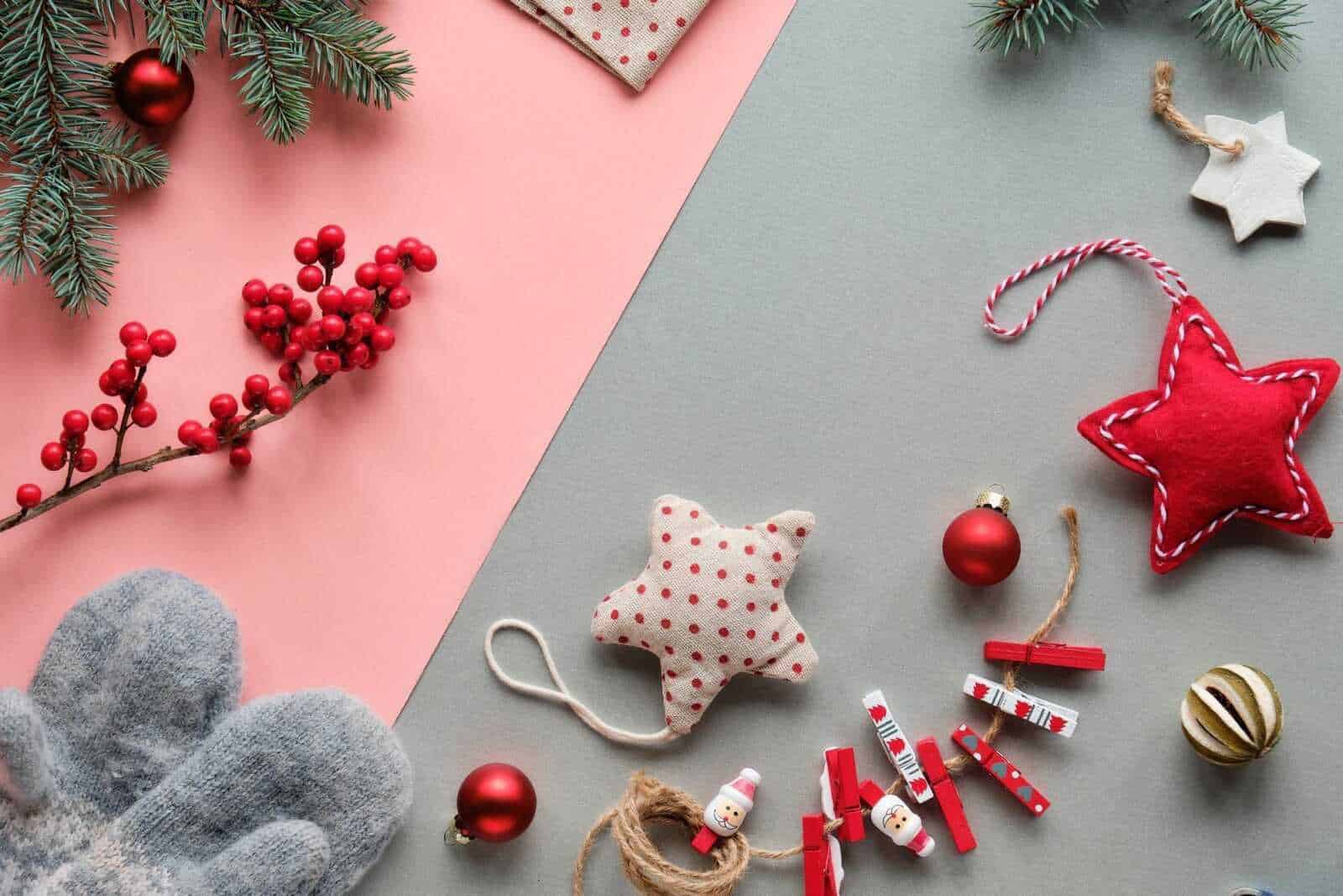 Addobbi natalizi rossi e decorazioni di Natale fatte a mano, come stelle e palline, su sfondo colorato per festeggiare le festività in modo originale e creativo.