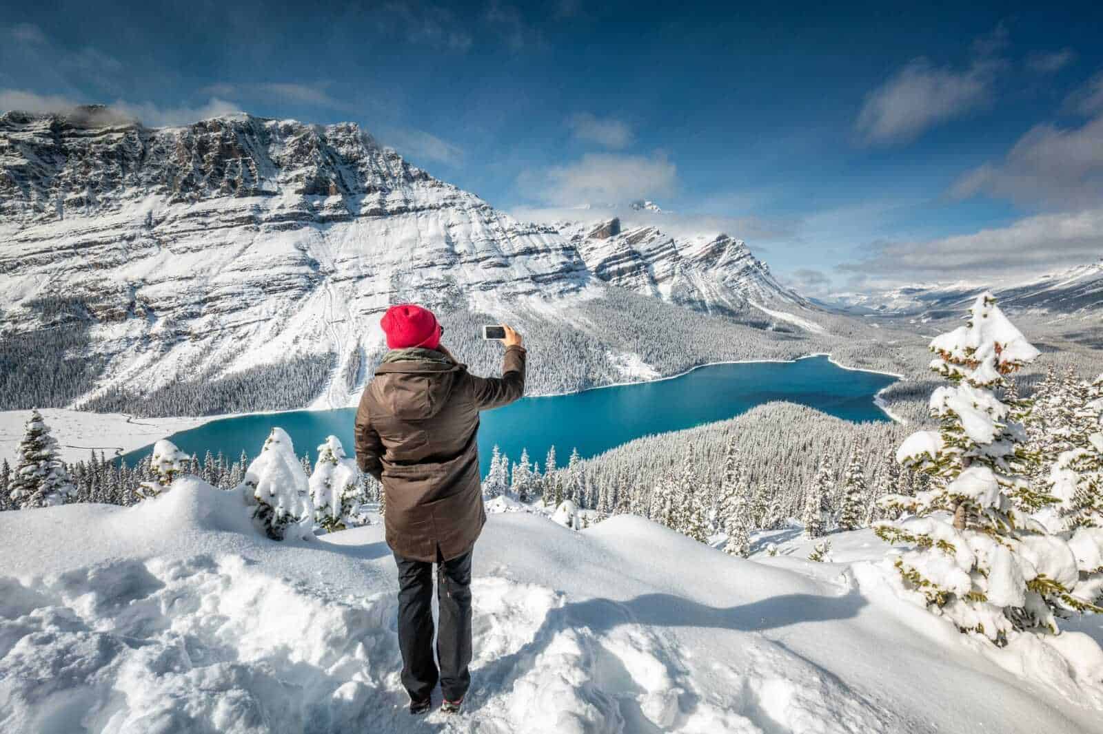L'altimetria di una persona che scatta una foto al lago ghiacciato circondato da montagne innevate.
