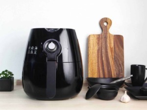 Velocità di cottura con friggitrice ad aria nera su cucina moderna, accessori di cucina eleganti con piante e spezie, stile minimalista e funzionale per ricette sane e veloci.