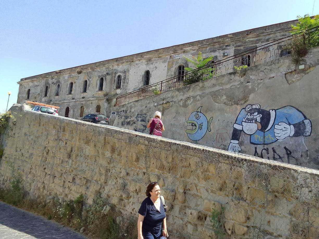 Colorata street art graffiti su muro di pietra antico con persone che passeggiano, scenario urbano storico e moderno, wall art creativa, ambiente cittadino, arte urbana.