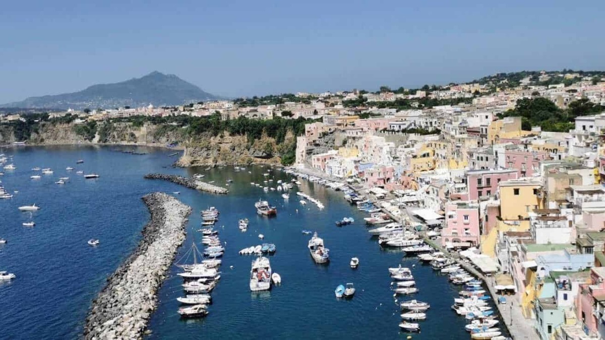 Vernazza, borgo costiero delle Cinque Terre in Italia, con case colorate, porticciolo e barche nel mare, circondato da scogli e colline blu nel cuore della Riviera ligure.
