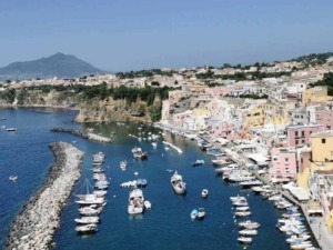 Vernazza, borgo costiero delle Cinque Terre in Italia, con case colorate, porticciolo e barche nel mare, circondato da scogli e colline blu nel cuore della Riviera ligure.