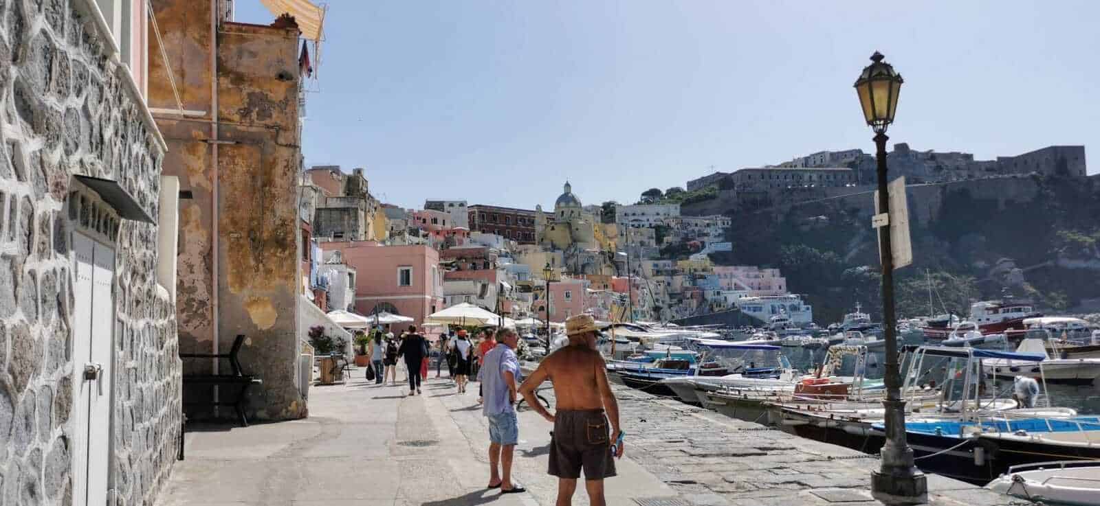 Barca di molo con yacht e case colorate sullo sfondo nel Porto, durante una giornata soleggiata, con turisti che passeggiano lungo il lungomare