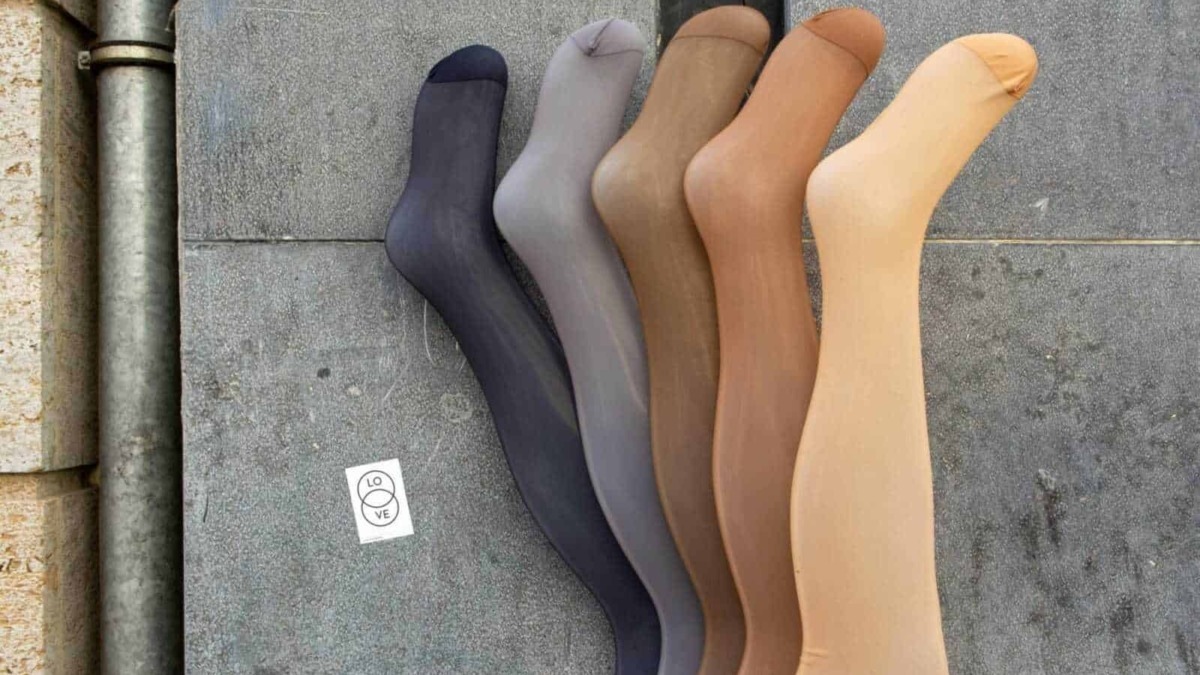 Calze colorate in vari toni su pavimentazione urbana, perfette per completare look casual e alla moda. La varietà di colori include nero, grigio, marrone, beige e giallo, ideali per ogni stile.