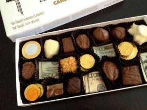 Deliziosa scatola di cioccolatini assortiti decorati con monete e banconote di carta, creata per celebrare occasioni speciali o come regalo di lusso.