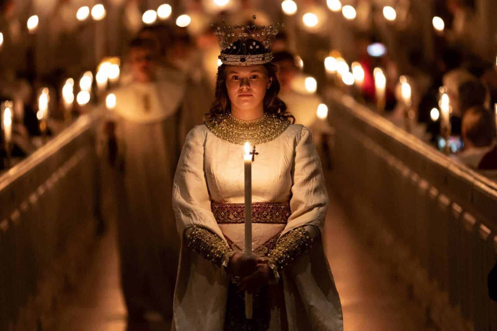 Candela liturgica e donna vestita in abito tradizionale, durante una cerimonia religiosa notturna in chiesa, con molte candele accese, atmosfera solenne e spirituale.