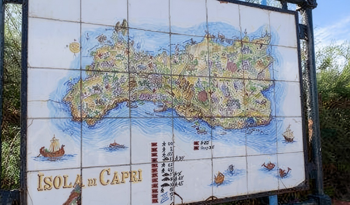 Carta dettagliata dell'isola di Capri, illustrando paesaggi, punti di interesse e mare circostante, situata all'aperto in un cartellone informativo.