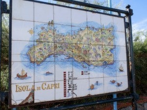 Carta dettagliata dell'isola di Capri, illustrando paesaggi, punti di interesse e mare circostante, situata all'aperto in un cartellone informativo.