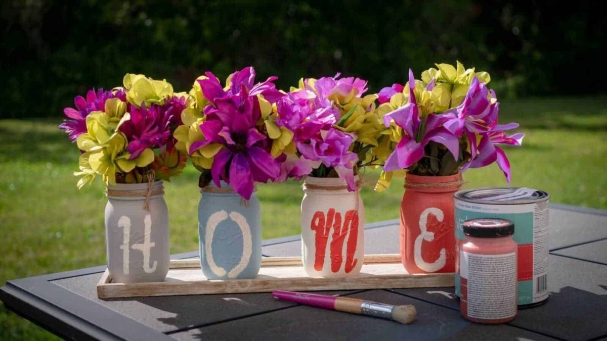 Vasi decorativi con fiori colorati, scritte Personalizzate, tavolo in giardino con vernice, pennello e barattoli di vernice, decorazioni floreali per esterni.